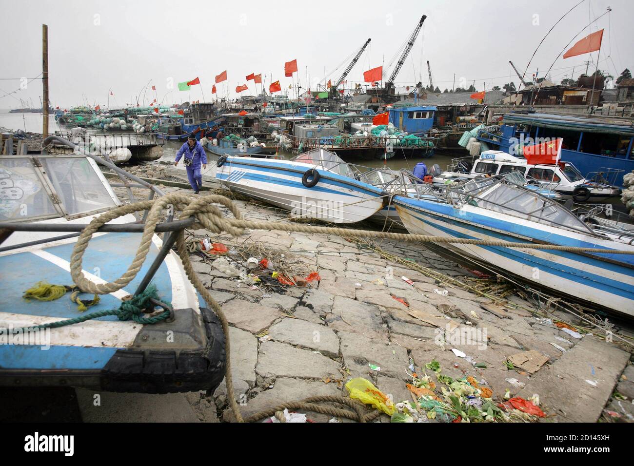 A fisherman steps off his boat at the harbour in Dongtan, where Dongtan Eco City is planned to be built, on Chong Ming Island southeast to Shanghai January 21, 2008. British Prime Minister Gordon Brown hailed a new era of environmental cooperation between Britain and China on January 19, 2008 and called for a renewed drive for a world trade deal. Brown visited a highly efficient gas-fired power station in Beijing and studied the plans for the environmentally friendly Dongtan Eco City to be built near Shanghai, in efforts to underline his keenness to cooperate with China on fighting global warm Stock Photo
