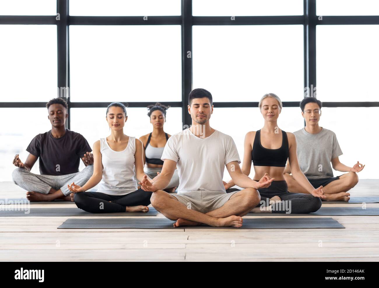 Group Meditation. Young Multiethnic Men And Woman Meditating Together In Lotus Position Stock Photo