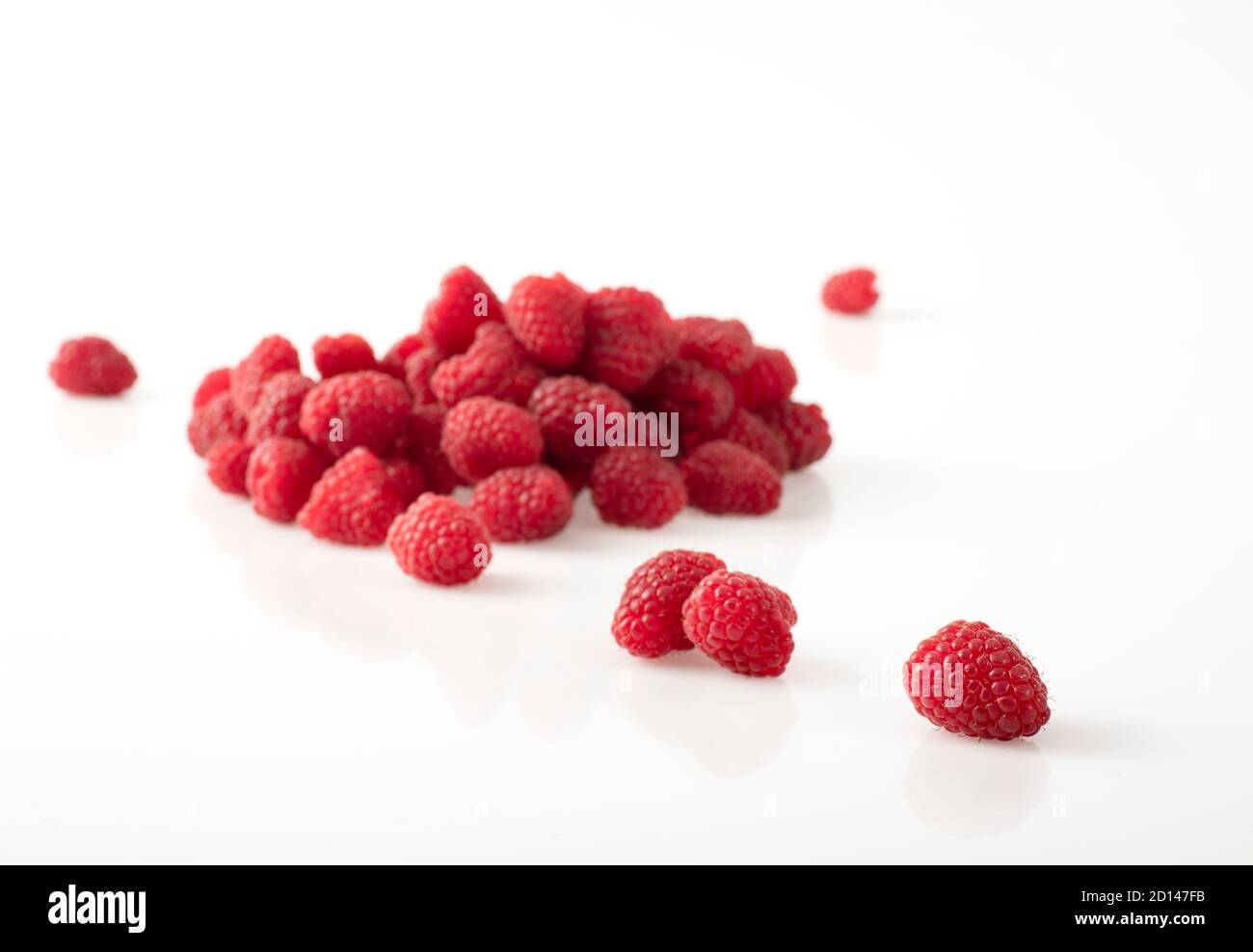 Fresh raspberries placed on a white, shiny background. Stock Photo