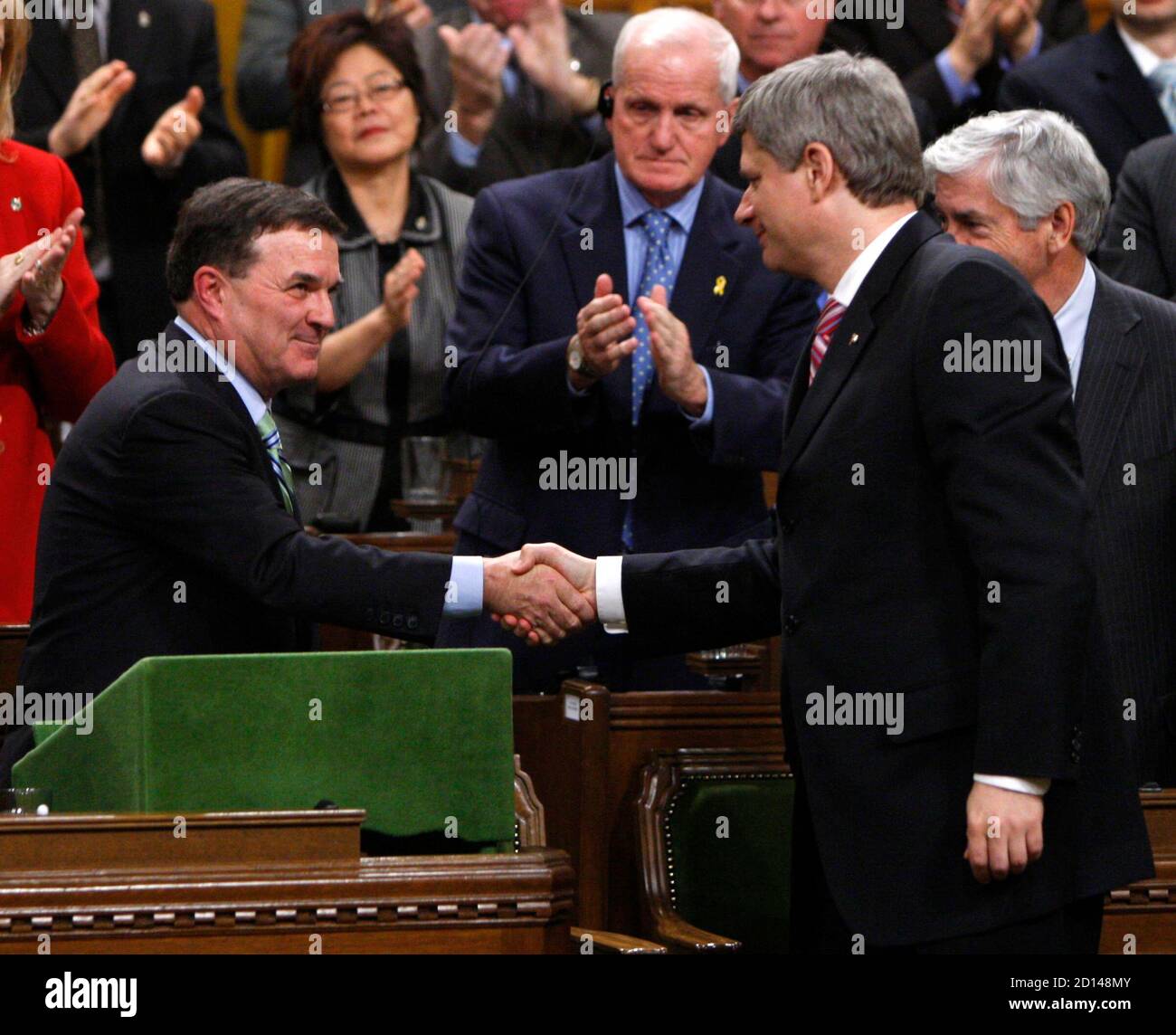 Canada's Finance Minister Jim Flaherty (L) shakes hands with Prime Minister Stephen Harper after delivering the government's fiscal update in the House of Commons on Parliament Hill in Ottawa November 27, 2008. The Canadian economy has slipped into recession and the federal coffers are on the verge of running dry for the first time in 13 years, the government said on Thursday in a report that raised the prospect of an early election.     REUTERS/Chris Wattie (CANADA) Stock Photo