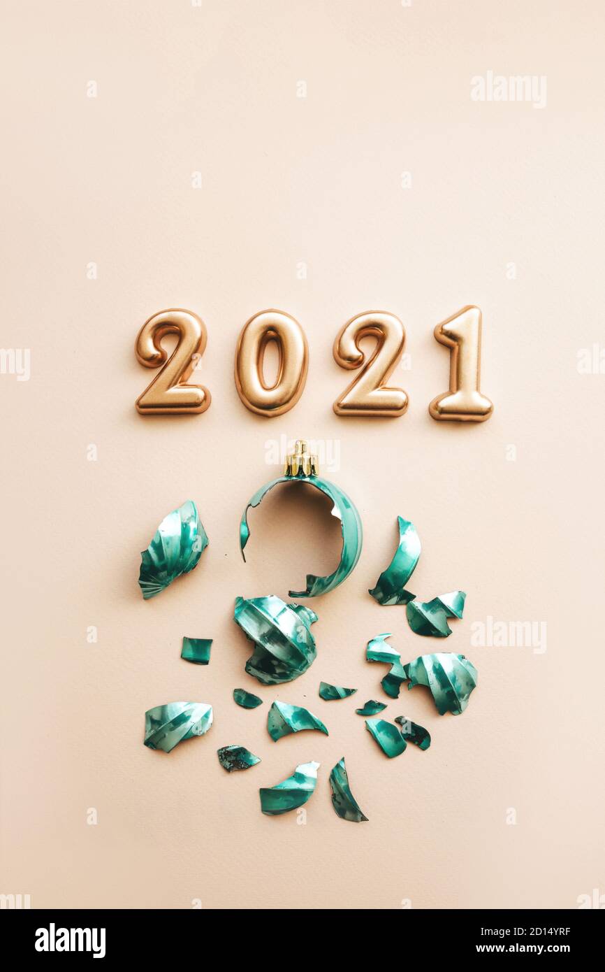 Gold numbers 2021 next to a broken Christmas tree toy on a pink background. Stock Photo