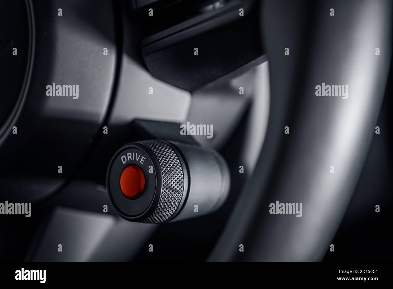 Supercar Engine Ignition Red Push Button Start on the Vehicle Steering Wheel Close Up. Modern Automotive Theme. Stock Photo