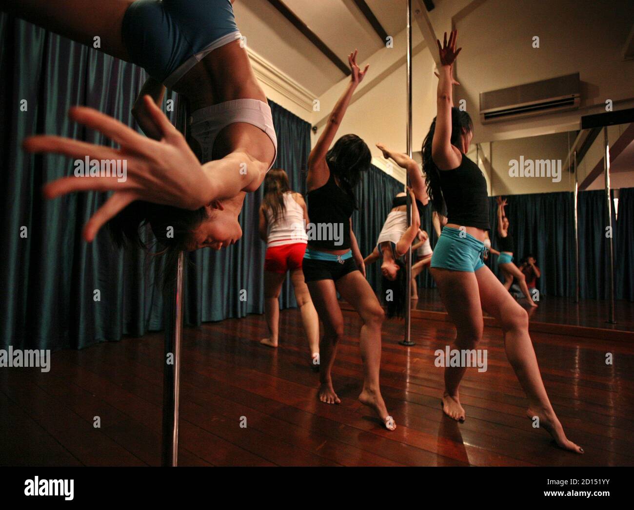 Dancers practice at a pole dancing school in Singapore March 9, 2006. The dance  school is the first in Singapore to introduce pole dancing which is a new  form of exercise adopted