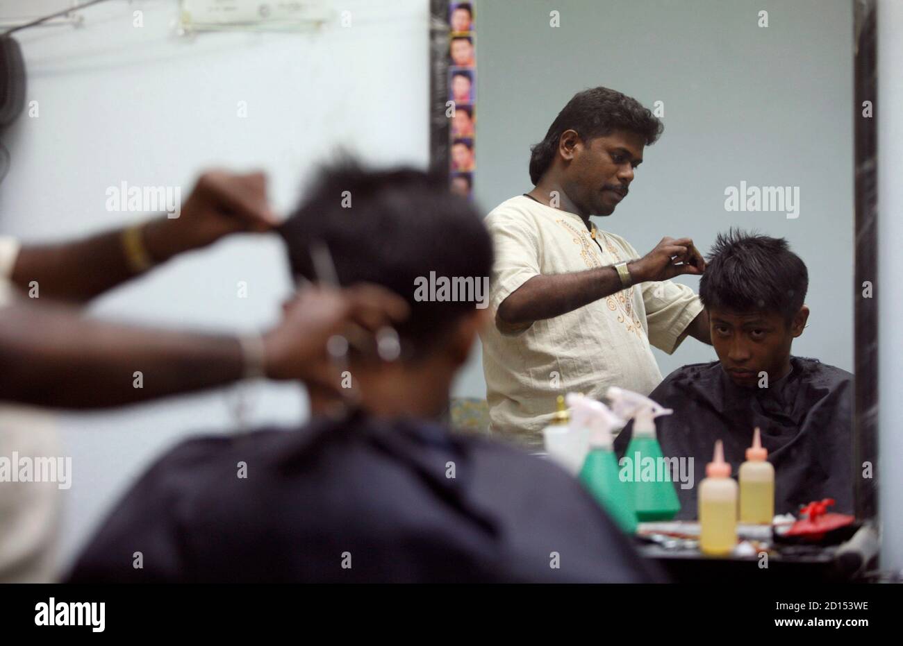Mutu Mari, a foreign worker from India, is reflected in a mirror as he works at a barber shop in Putrajaya January 8, 2008. Malaysia has suspended the recruitment of workers from India and Bangladesh, the government said on Tuesday, in a move one official said could be linked to a recent uproar about Malaysia's treatment of its ethnic Indians.   REUTERS/Bazuki Muhammad (MALAYSIA) Stock Photo