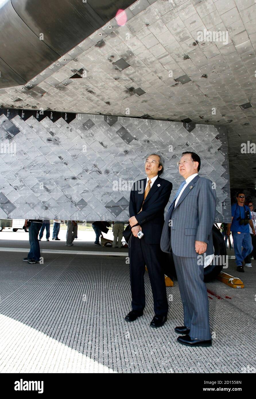 JAXA vice president Kaoru Mamiya (R) and Director of JAXA Manned Spaceflight Yuichi Yamaura stand beneath a wing on the space shuttle Discovery after it landed at the Kennedy Space Center in Cape Canaveral, Florida June 14, 2008. Japanese astronaut Akihiko Hoshide was onboard the spacecraft for the mission to the International Space Station.    REUTERS/Pierre DuCharme (UNITED STATES) Stock Photo