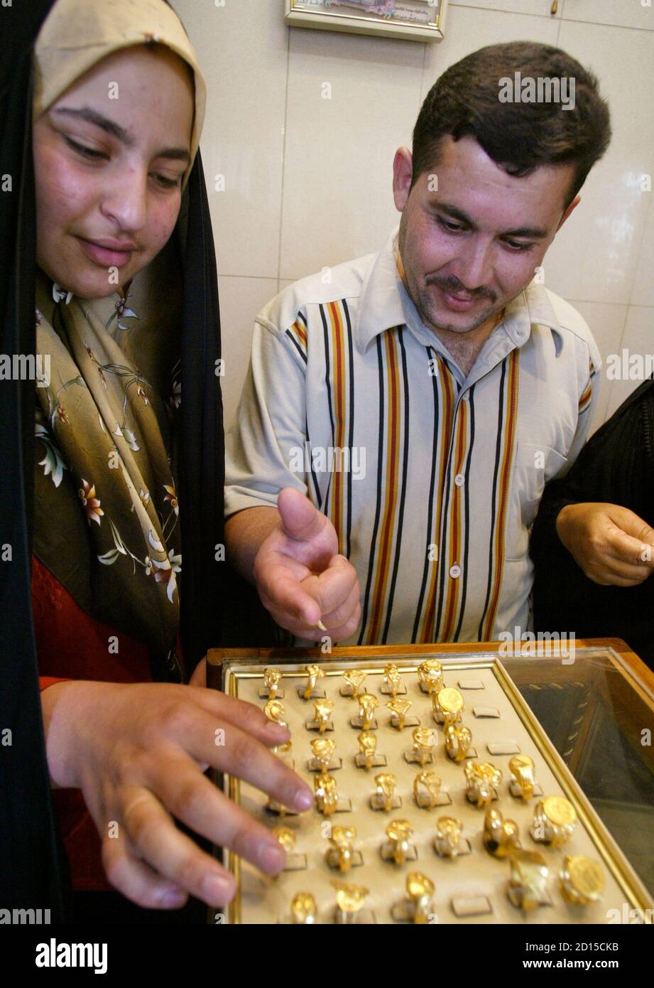 Ayser Ameir Ali (R) and his fiancee Zainab Qasim Hasan look at display of rings as they shop for gold before their upcoming wedding in Baghdad April 11, 2006. Iraqi men traditionally give presents of gold to their brides-to-be ahead of the nuptials. Gold raced above the fabled $600-an-ounce level on Tuesday, its highest since December 1980, as investors and funds poured money into precious metals to diversify their portfolios brought on by worries about inflation, Middle East tensions and uncertainties over the dollar's outlook.    REUTERS/Faleh Kheiber Stock Photo