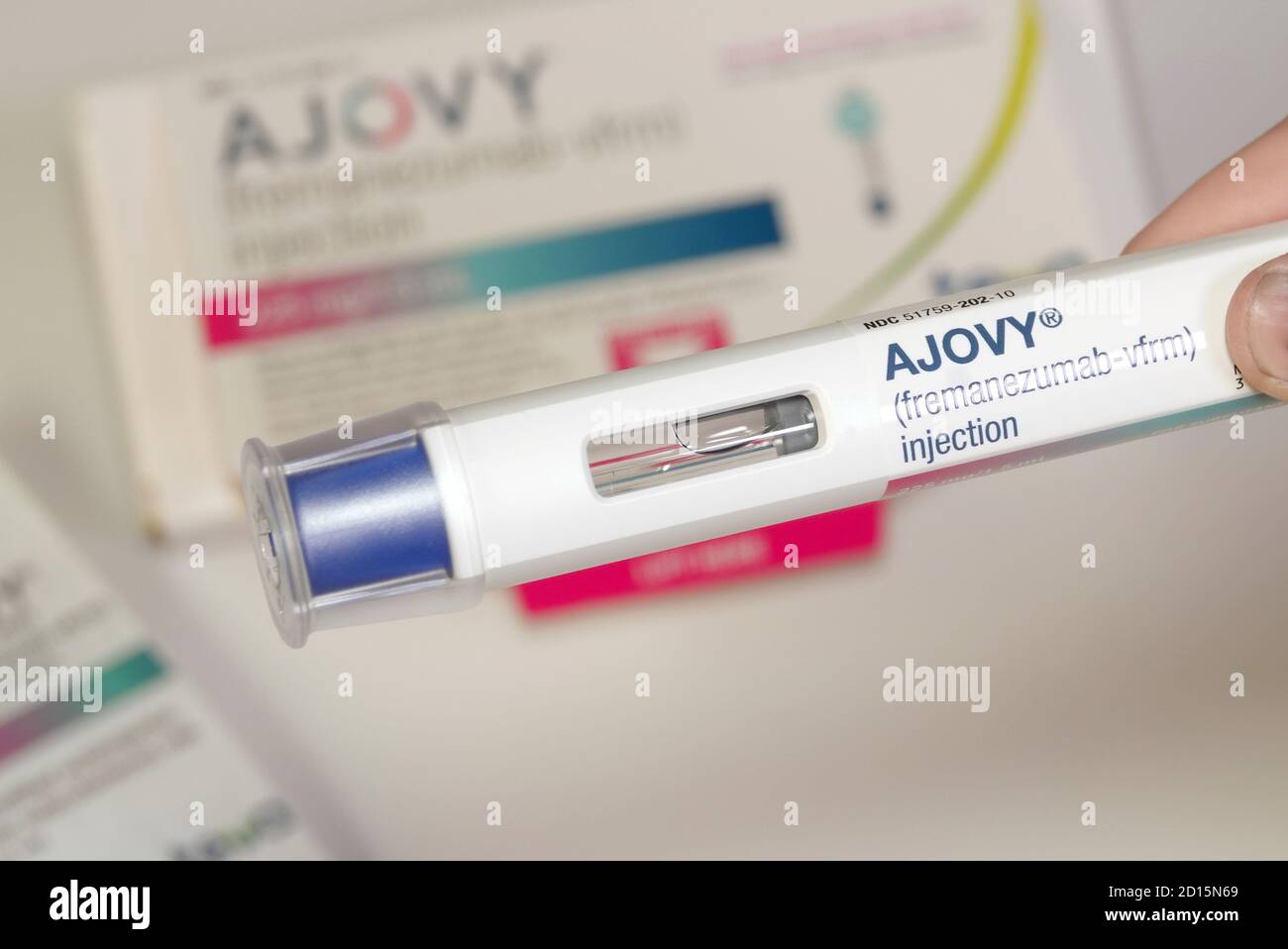 Ajovy, one of four newly FDA approved migraine preventatives. Close up of the auto injector held up in front of product packaging. Stock Photo