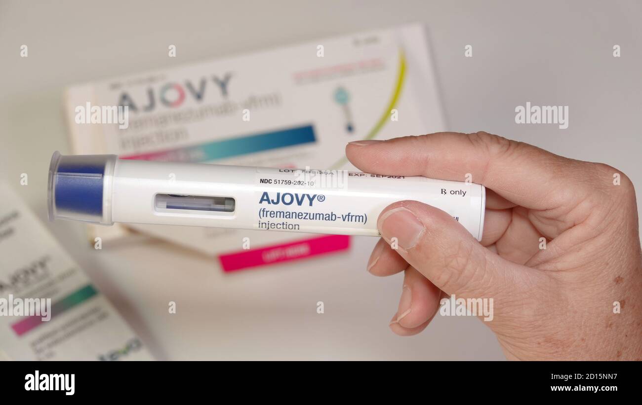 Ajovy, one of four newly FDA approved migraine preventatives. Close up of the auto injector held up in front of product packaging. Stock Photo