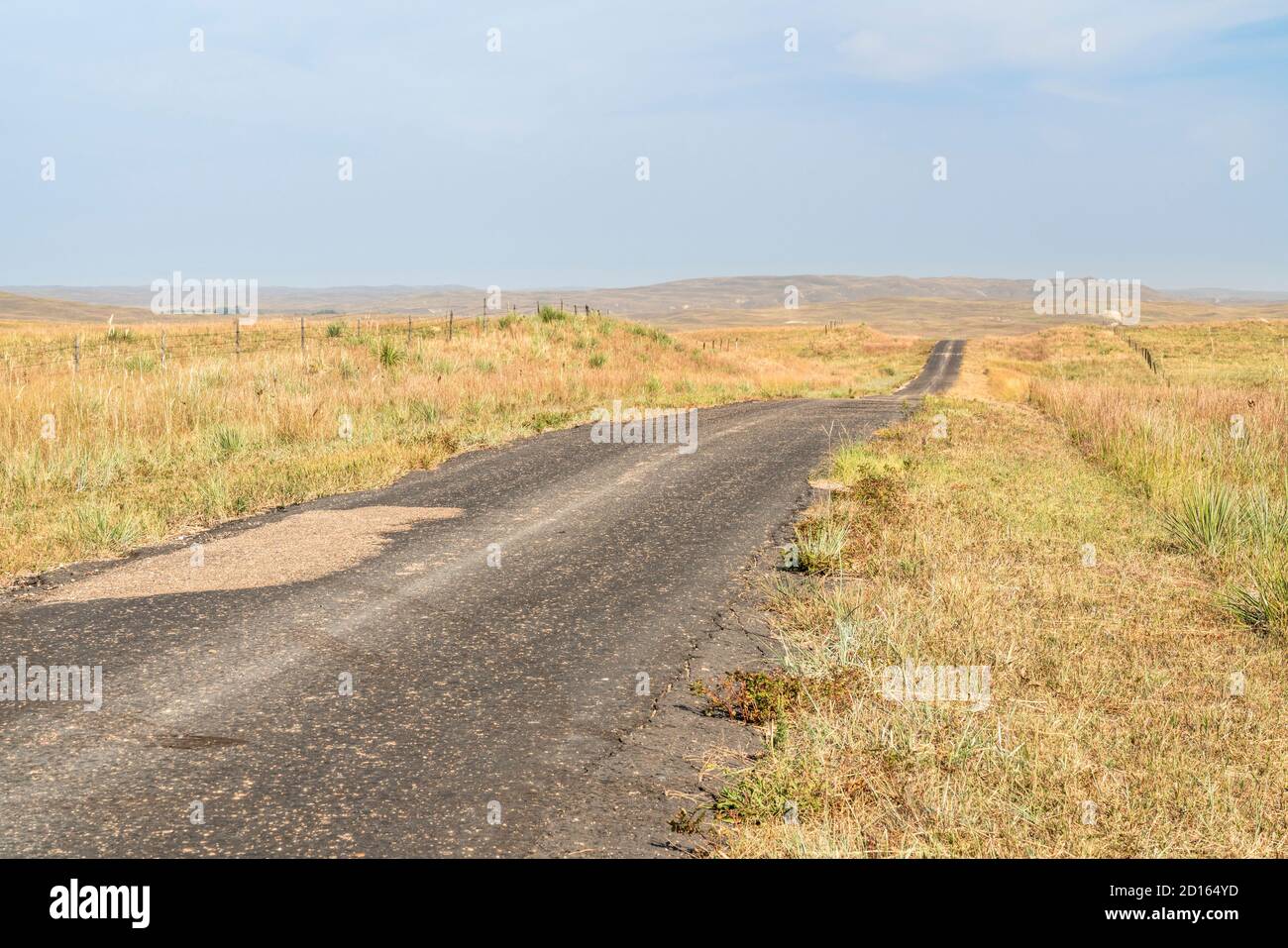 narrow and rough rural highway in Nebraska Sandhills,  midday hazy scenery affected by wildfire smoke from Colorado and Wyoming Stock Photo