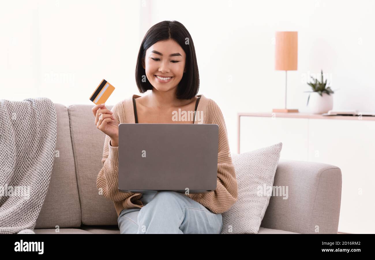 Young asian woman making purchases sitting on the couch Stock Photo