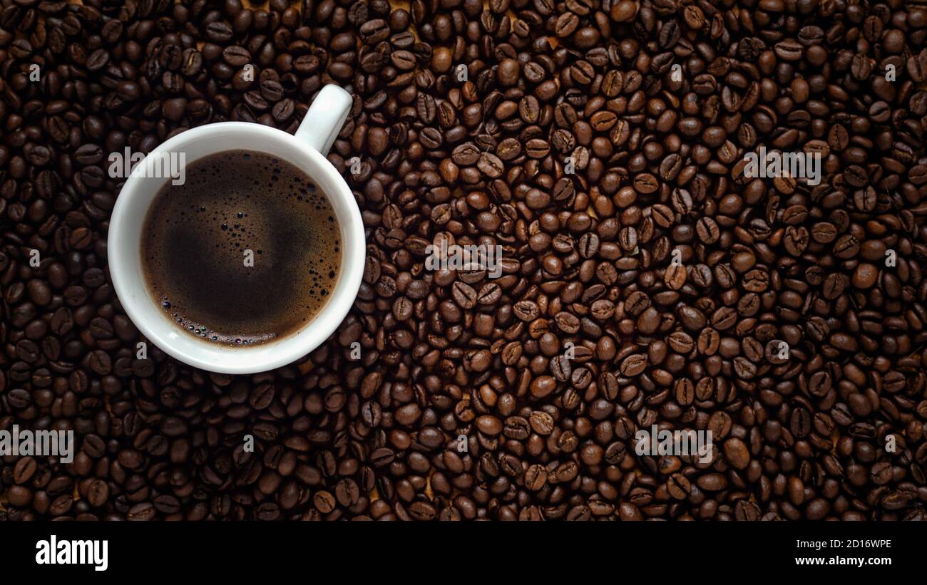 Flat lay of coffee cup on dark roasted arabica coffee beans background ...