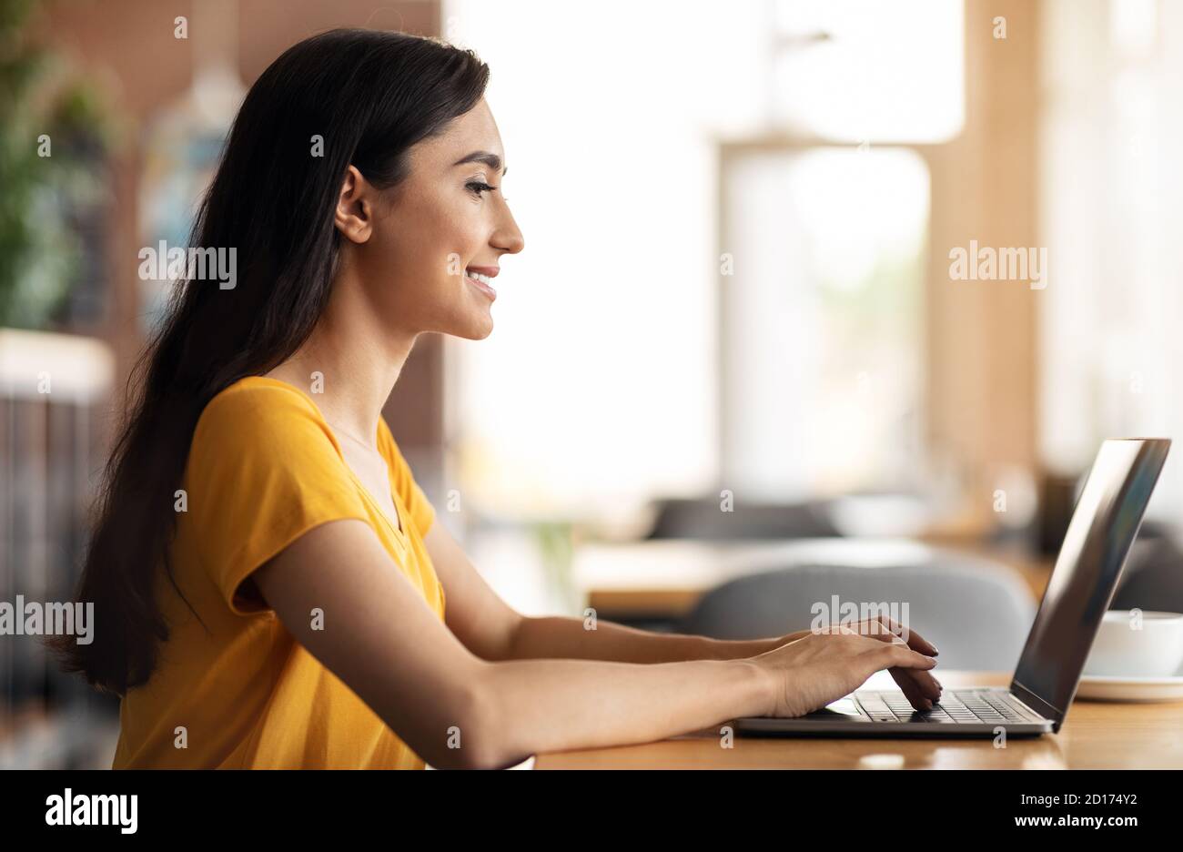 Smiling arab woman using laptop while sitting at cafe Stock Photo