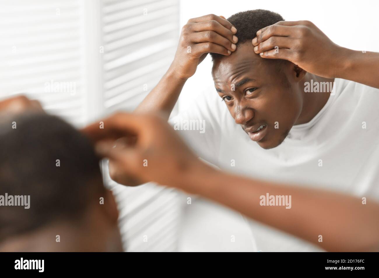 African Man Having Dandruff Problem Looking In Mirror In Bathroom Stock Photo