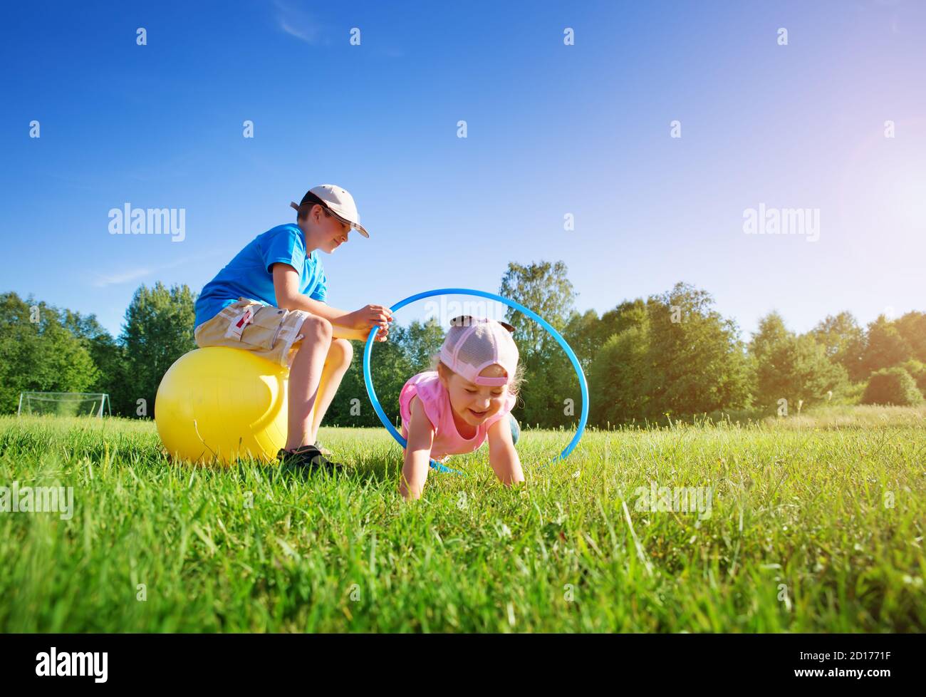 Children are playing on the sport field with hula hoop and rubber