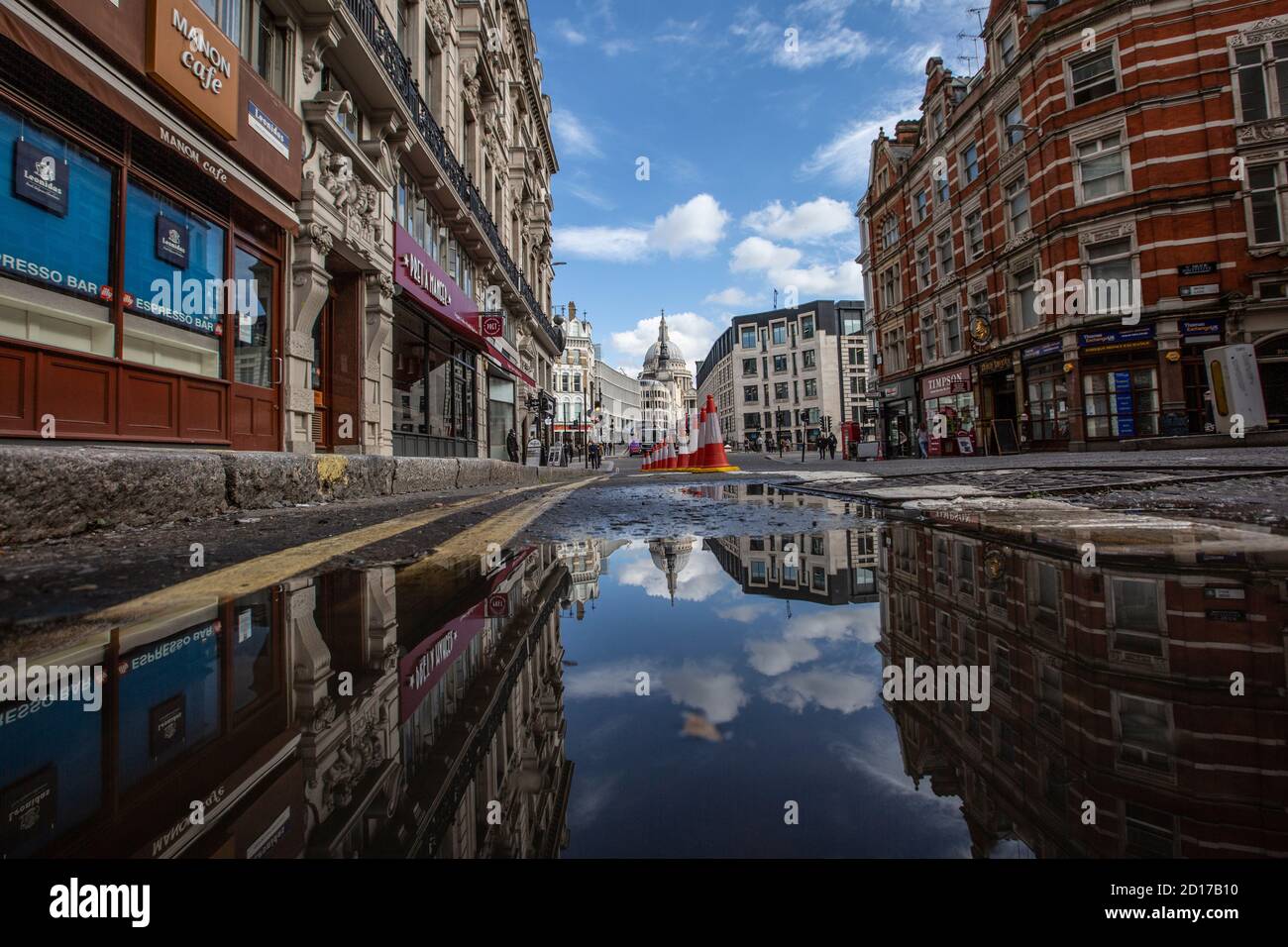 Buildings reflected in a puddle in the road at Queen Victoria Street, City of London, Central London, England, UK Stock Photo