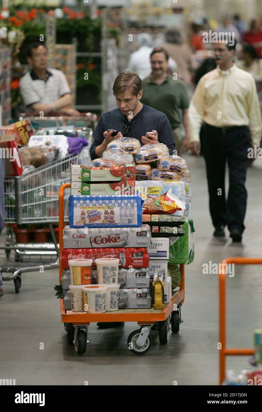 A shopper checks his cell phone while shopping at the Costco Warehouse in  Arlington, Virginia, May 29, 2008. Costco Wholesale Corp., the biggest U.S.  warehouse club operator, reported a 32 percent jump