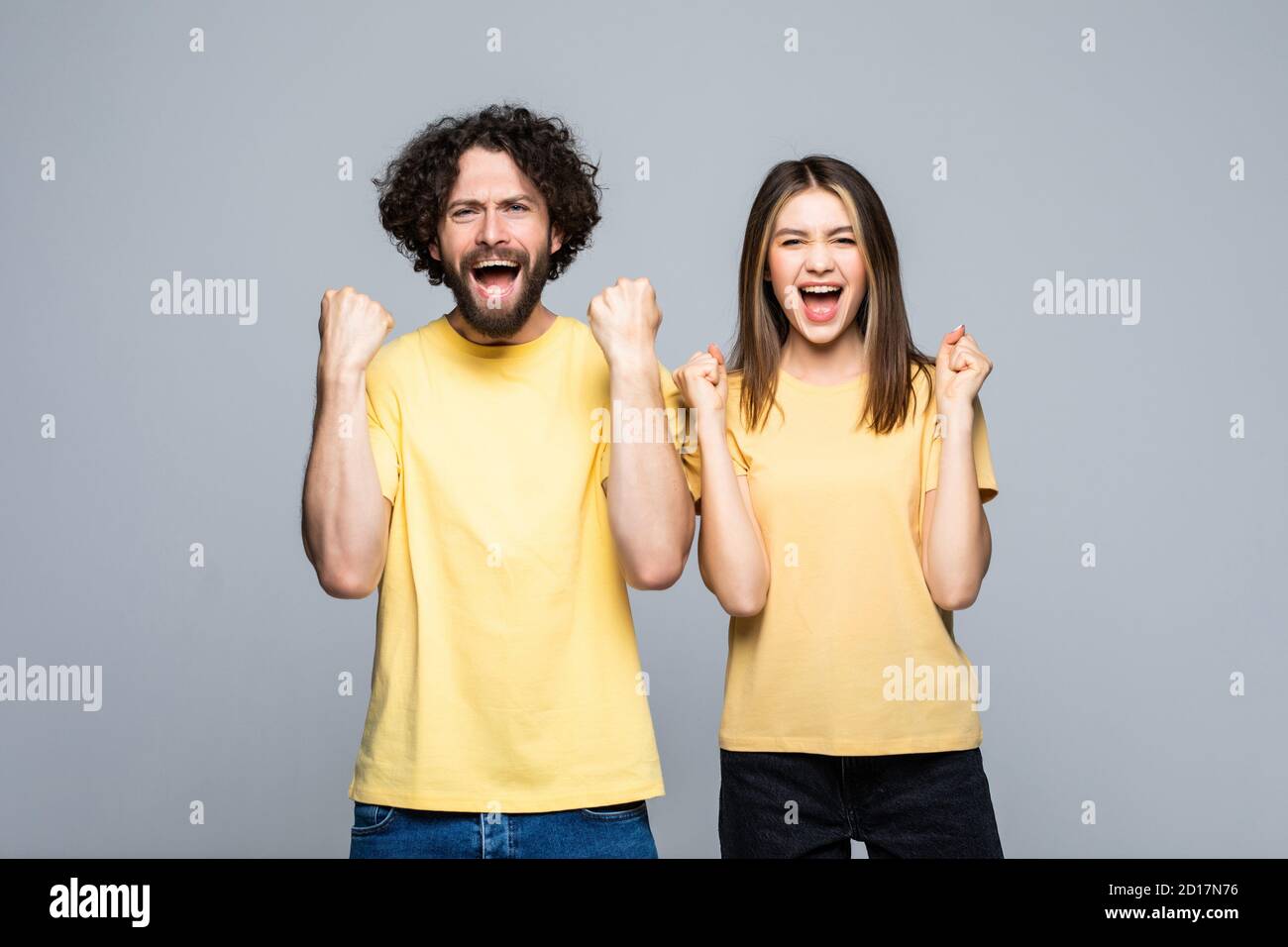 Excited happy young couple winners celebrate win motivated by triumph rejoice victory success together isolated on white grey background Stock Photo