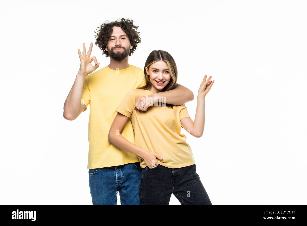 Full length portrait of a cheerful smiling couple hugging and showing ...