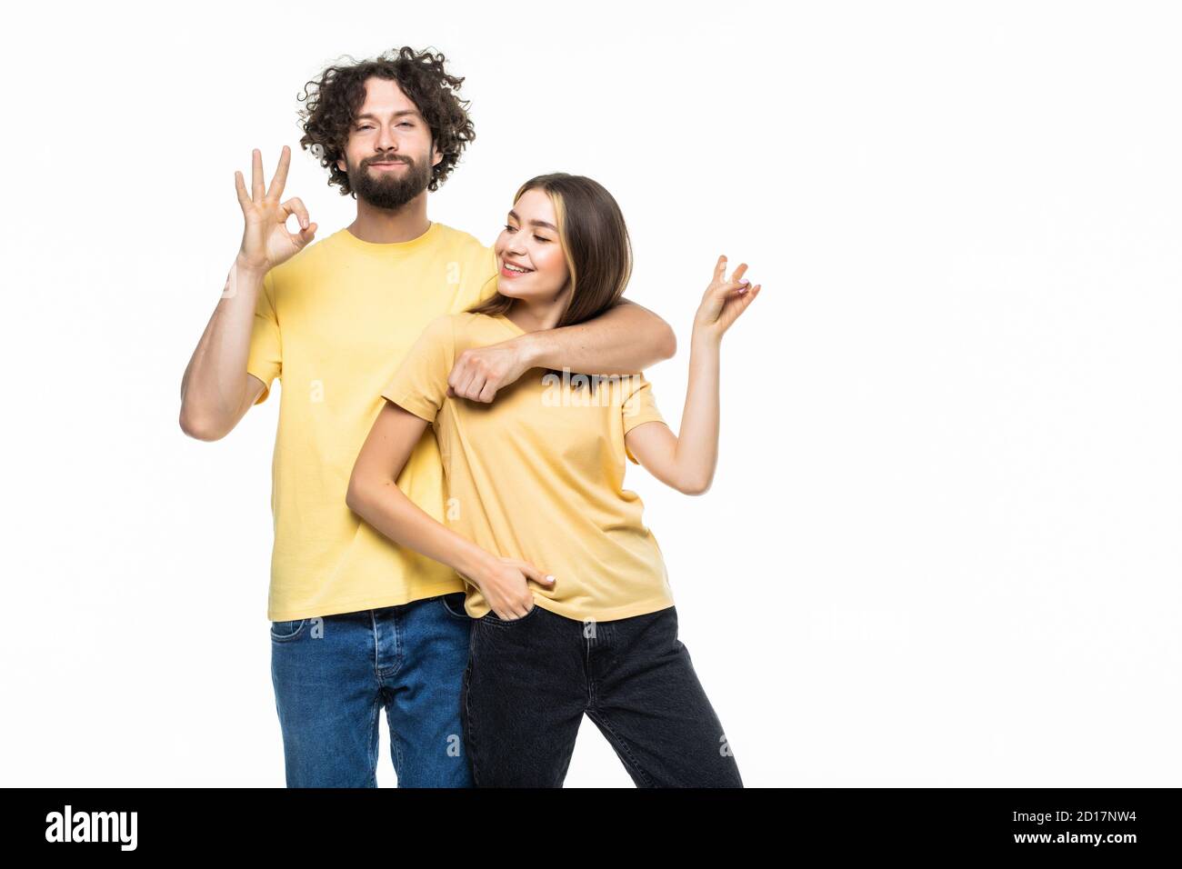 Full length portrait of a cheerful smiling couple hugging and showing ...