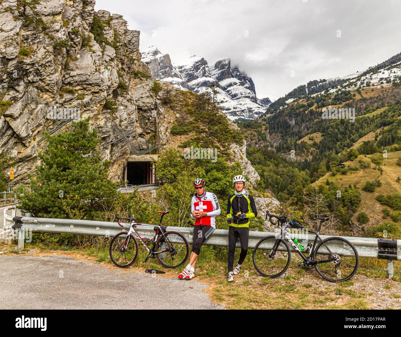 "As long as you can still talk, you are not trying hard enough". Talking in a break on the mountain with a magnificent view is a nice alternative. With racing bikes through the Alps at Leuk, Switzerland Stock Photo