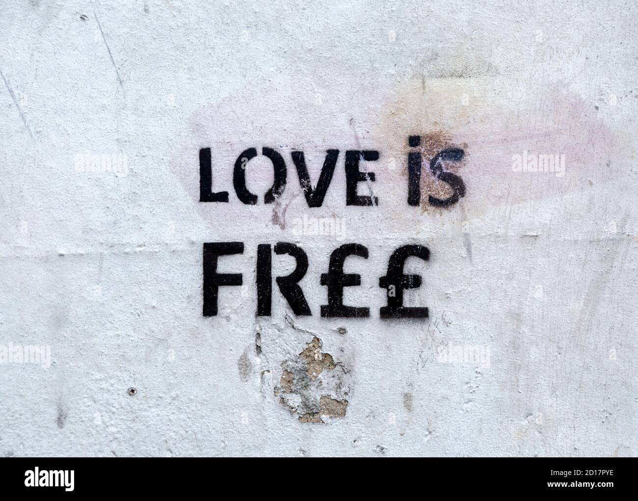 Stencilled graffito message 'Love is Free'  on white wall, Newbury, Berkshire, England, UK Stock Photo
