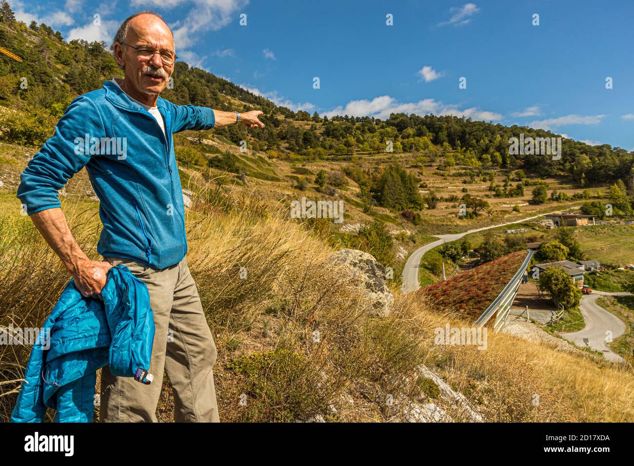 Bread-Baking workshop in Goppenstein-Erschmatt, Switzerland. Edmund Steiner points to the rye fields above Erschmatt. Rye from the Valais has been cultivated on the terraces for centuries. A tour of the village, including vivid descriptions of the hard life back then, is part of the rye bread baking workshop. Stock Photo