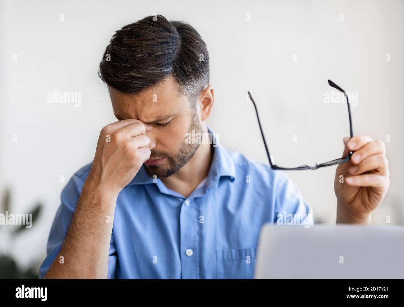Eyes Pain. Millennial businessman massaging nosebridge, tired after