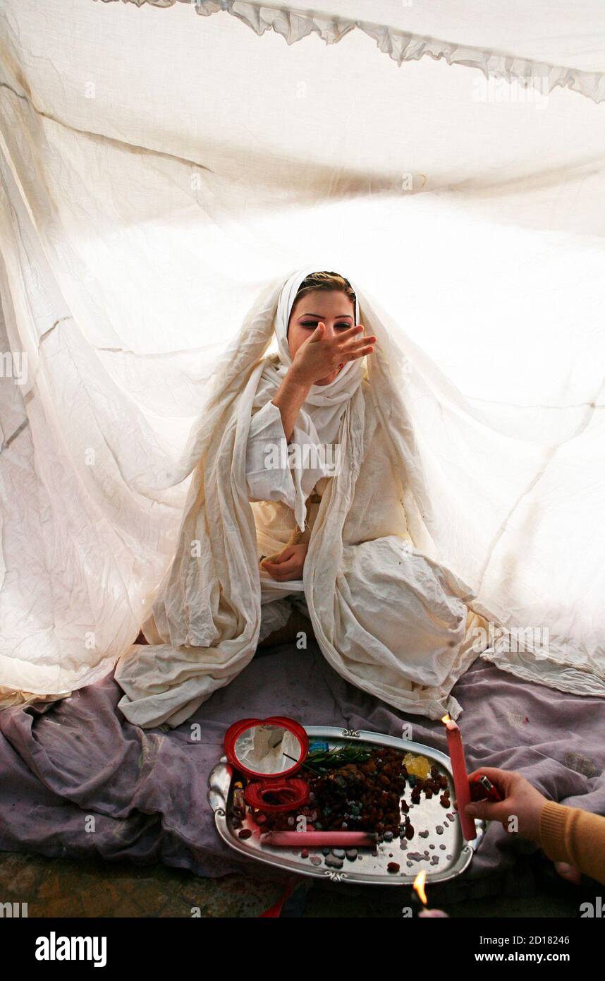 Iraqi Mandean bride Mary Ayed sits in a tent and eats special sweets at her wedding ceremony in the Damascus suburb Jaraman December 2,2007. Mandean brides must have their virginity checked by other women before they can be baptised. Mandean scholars trace the obscure religion's roots to Adam, whom they say lived 980 million year ago - pushing mankind's origins far earlier than those proposed by science. Almost every ceremony in the religion involves water, and baptism is regarded as the means to ask for forgiveness of sin.  REUTERS/Khaled al-Hariri   (SYRIA) Stock Photo