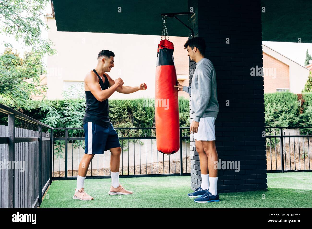 two men dressed in sportswear hit a punching bag Stock Photo