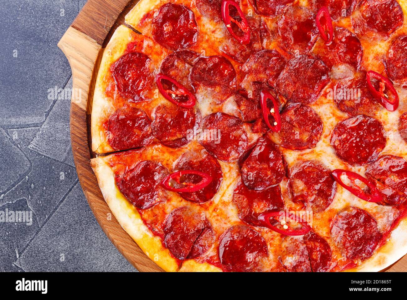 Pepperoni pizza on wooden board on a dark background. Close-up Stock Photo