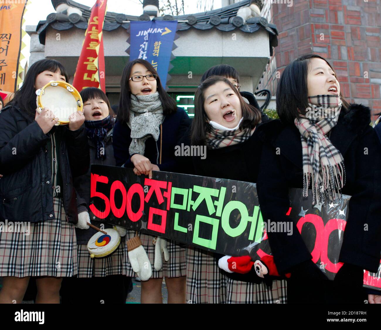 High school juniors encourage their seniors as they arrive to take a college entrance exam in front of an exam hall in Seoul November 12, 2009. About 670,000 high school seniors and graduates began taking the government-sponsored College Scholastic Ability Test on Thursday. The Korean characters read: 'We hope for a perfect score'.  REUTERS/Lee Jae-Won (SOUTH KOREA EDUCATION SOCIETY) Stock Photo
