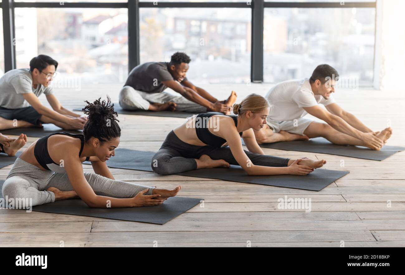 Diverse sporty men and women doing stretching exercises during group yoga lesson Stock Photo