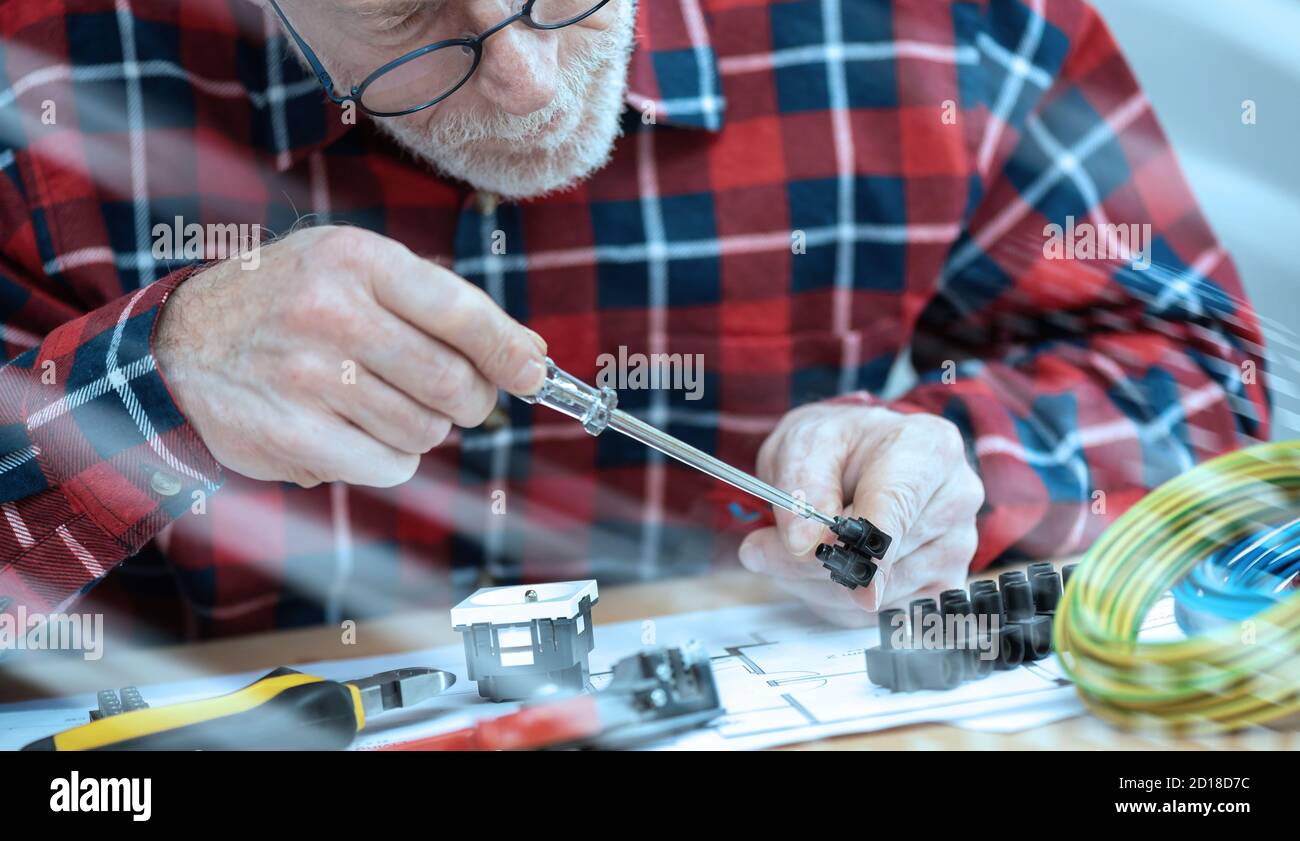 Senior electrician connecting wires in terminal block; light effect Stock Photo