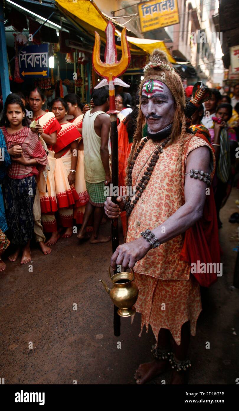 An man dressed as Hindu God Lord Shiva walks past Hindu devotees on the  occasion of Mahashivratri festival in Trakeshawar, about 50 km (30 miles)  west from the eastern Indian city of