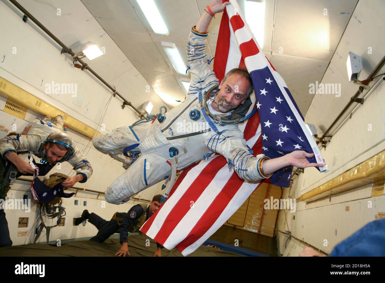 Space tourist Richard Garriott of the U.S. (R) and his back-up Nik Halik of  Australia hold their national flags as they undergo a zero-gravity flight  in the Moscow region July 9, 2008.
