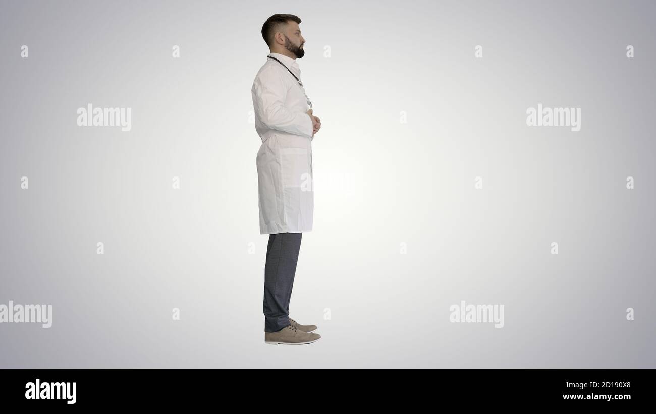Doctor with a beard standing on gradient background. Stock Photo