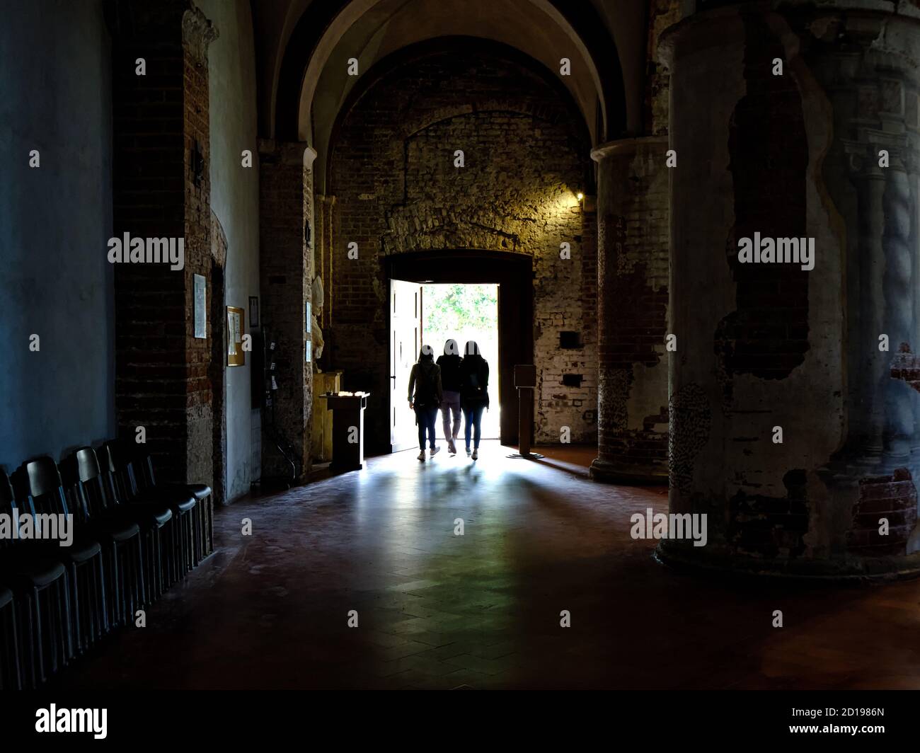 Three  young women come out of a church, Abbey Chiaravalle, Milan, Italy Stock Photo