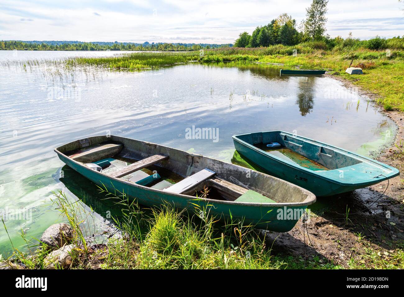 Plastic fishing boats on the bank of the lake in summer sunny day. Nature  of northern countries. Environmental landscape Stock Photo - Alamy