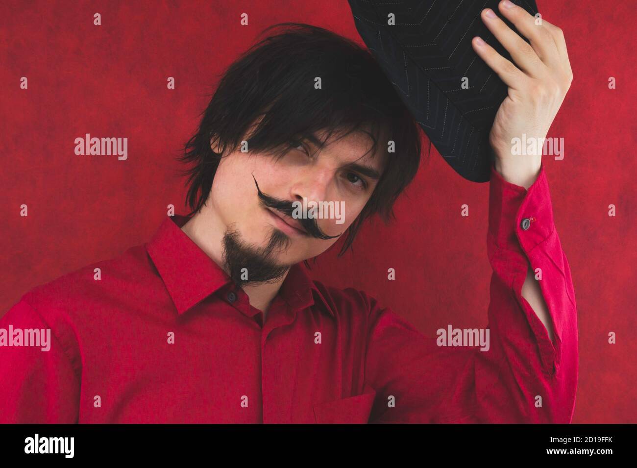 Young man takes off his hat. male portrait on the red background Stock Photo