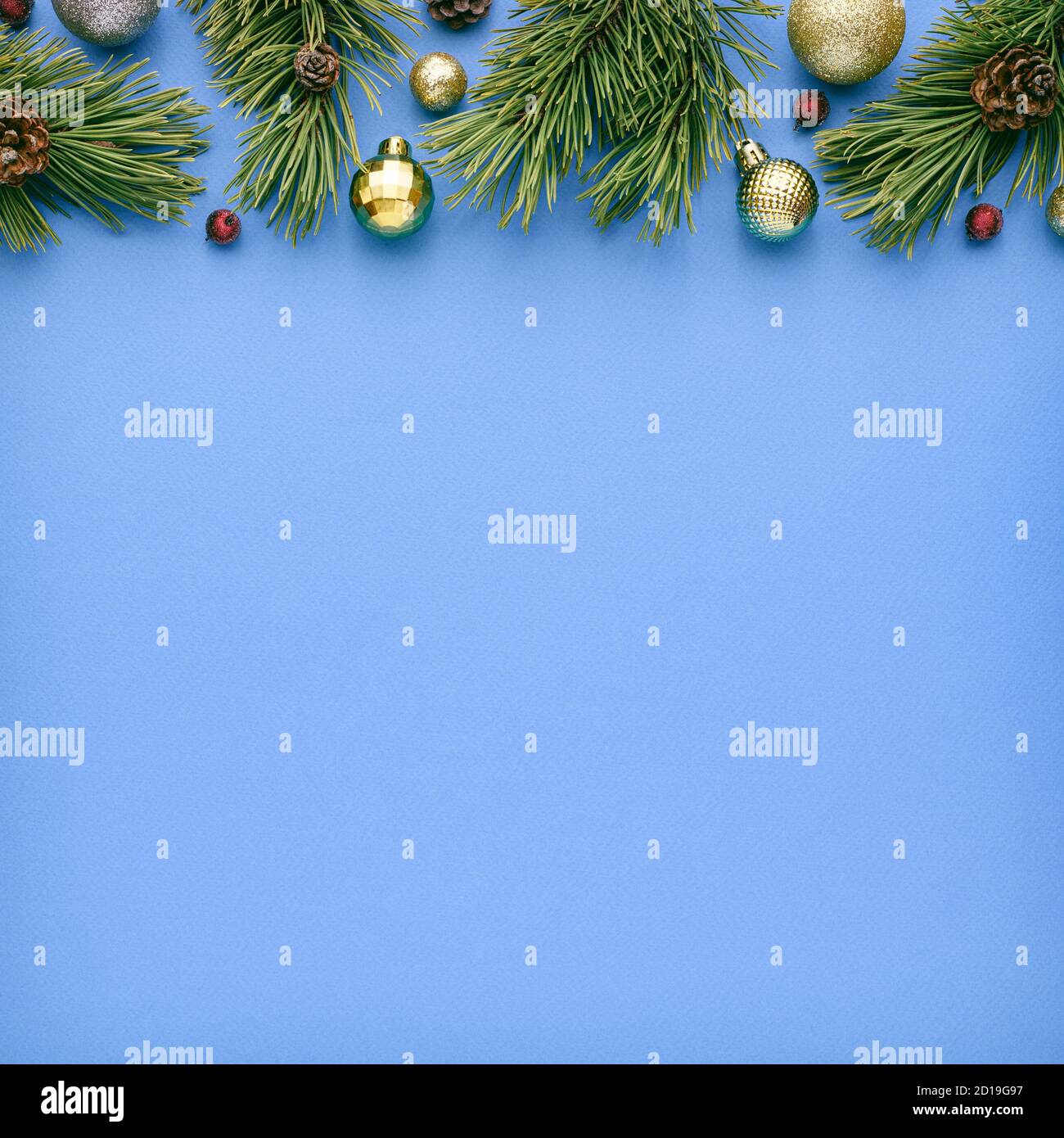 Square christmas card with fir decorations on blue background. Festive border with copy space for advertising text. Top view, flat lay Stock Photo
