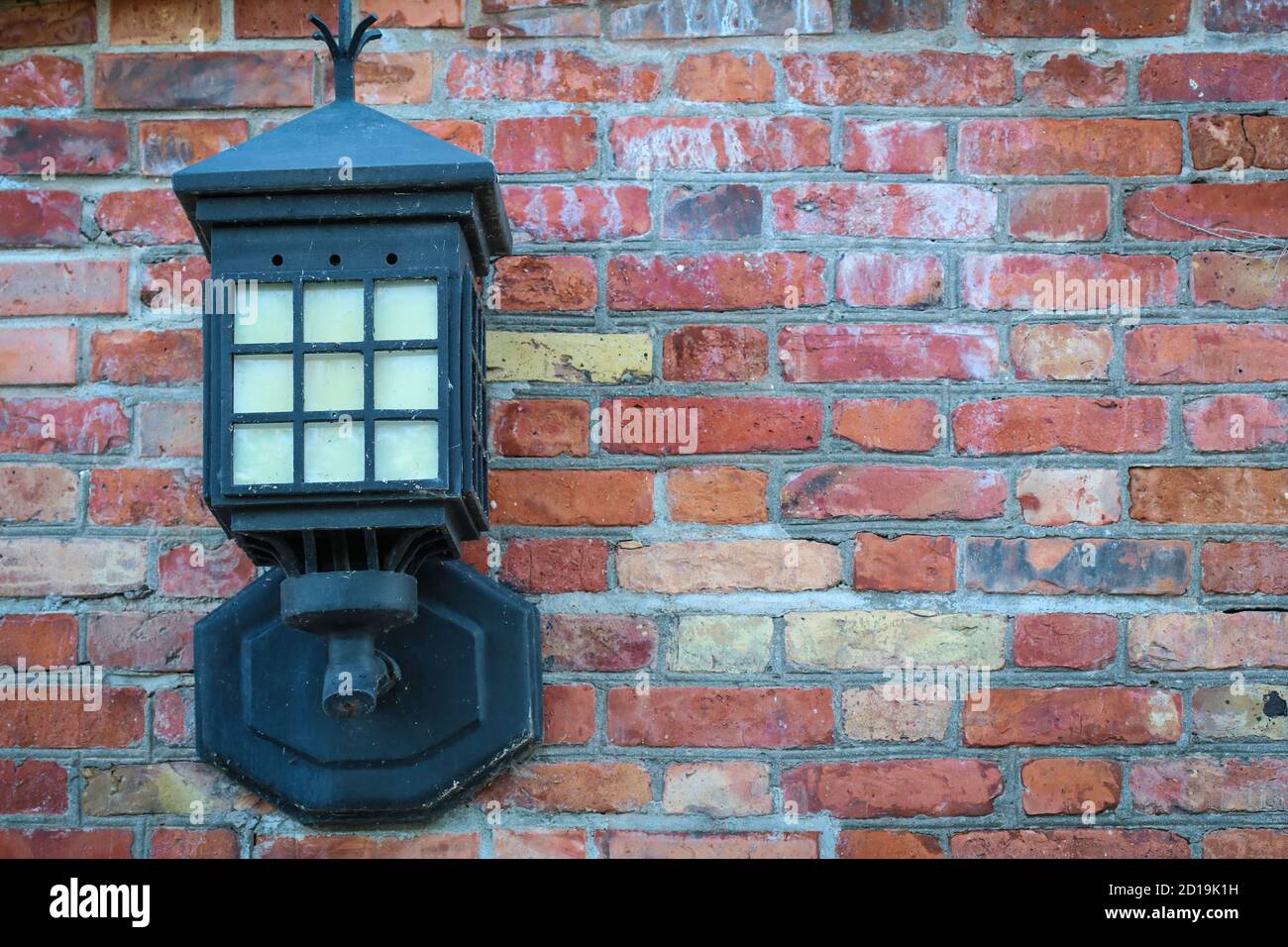 Old steel electric lantern attached to red brick wall Stock Photo