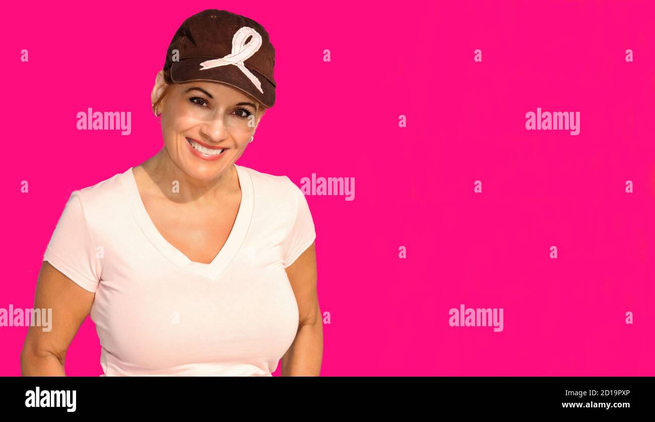 Beautiful Woman Wearing a Hat With a Pink Ribbon Isolated on a Pink Background in Support of Breast Cancer Awareness Stock Photo