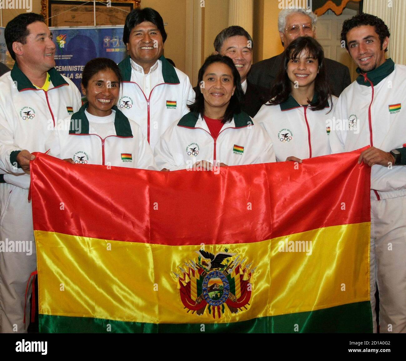 Members of the Bolivian Olympic team (L-R) Cesar Menacho taking part in sports shooting, Sonia Calisaya taking part in athletics, Maria Teresa Monasterios taking part in weight lifting, Karen Torrez taking part in swimming and Fradrique Iglesias taking part in athletics hold a national flag next to Bolivia's President Evo Morales (3rd L) pose at the presidential palace in La Paz July 28, 2008. REUTERS/Gaston Brito  (BOLIVIA)  (BEIJING OLYMPICS 2008 PREVIEW) Stock Photo