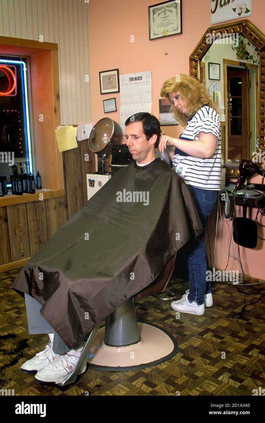 Female hair stylist barber cuts an adult male's hair Stock Photo