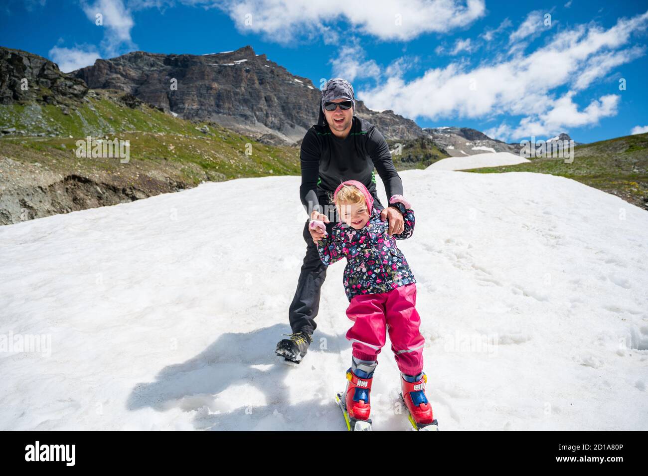 Happy father teaching his daughter to ski. Stock Photo
