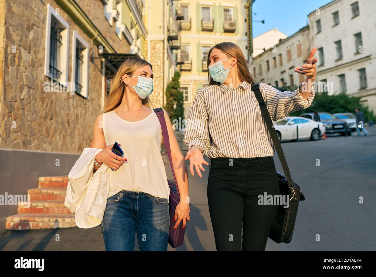 Office workers two women walking, wearing medical protective masks Stock Photo