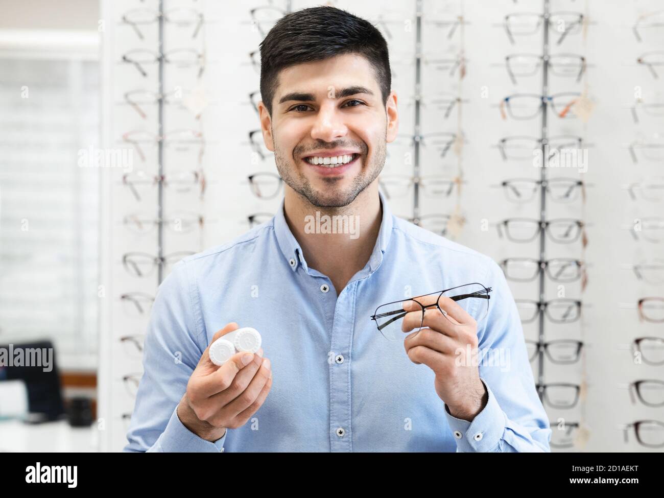 Smiling man showing to camera eyeglasses and contacts Stock Photo