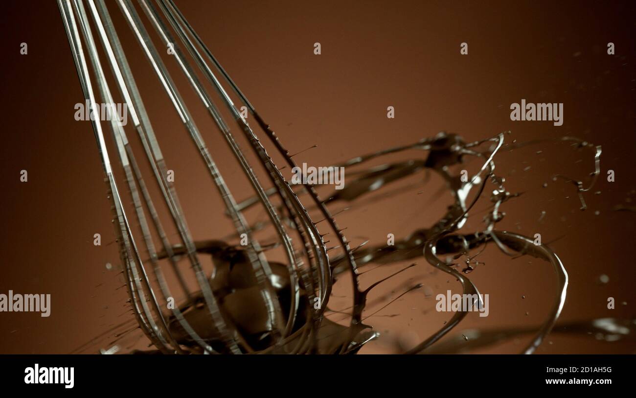 Freeze motion of wire whisk rotating hot melted chocolate, isolated on soft gradient background Stock Photo