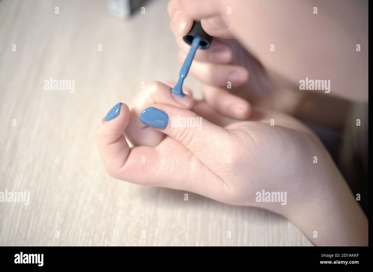 Young woman applying nail polish with brush from bottle, polishing painting  fingernails with blue color enamel, doing manicure at home, perfect healthy  nails care Stock Photo - Alamy