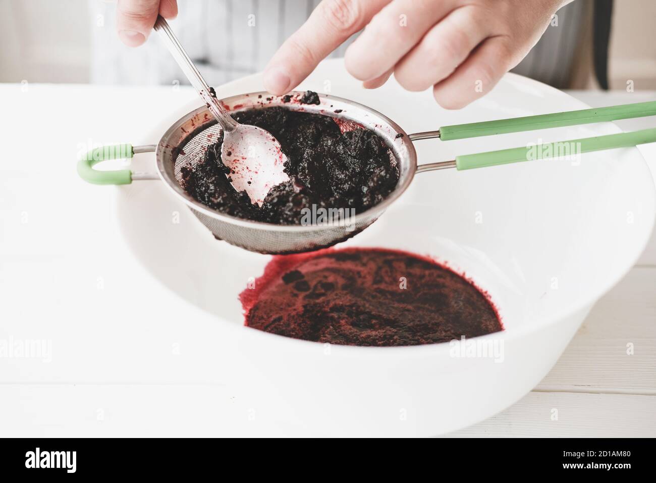 making berry puree. Woman strains berries through a sieve to make puree